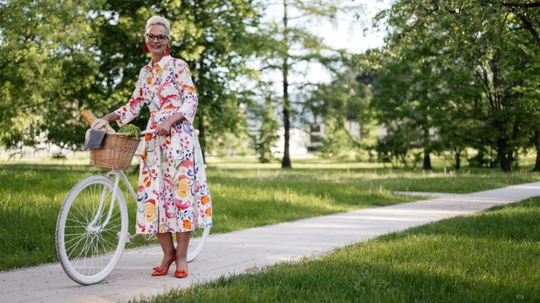 Senior woman smiling with her bicycle on a sunny path, enjoying the outdoors.